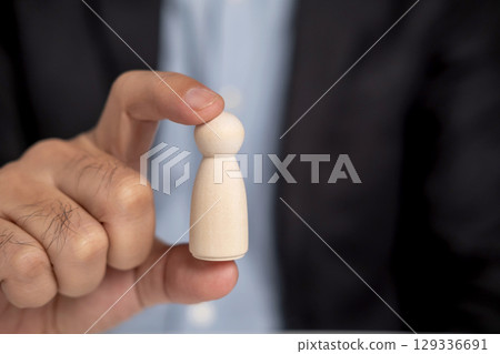 Close up businessman pick up leads wooden dolls. Close up businessman pick up leads wooden dolls. 129336691