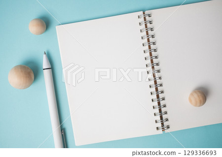 Workspace with empty notebook, pen and wooden ball on blue background. 129336693