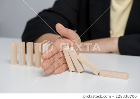 Hand stopping or preventing a falling block. Concept of hedging, risk elimination. Hand stopping or preventing a falling block. Concept of hedging, risk elimination. 129336700