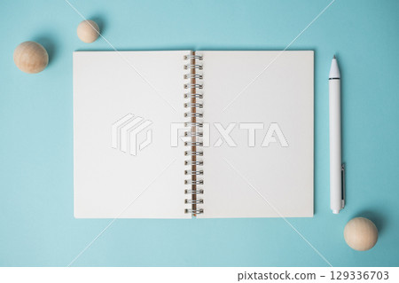 Workspace with empty notebook, pen and wooden ball on blue background. 129336703