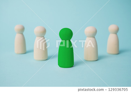 Green leads others from other wooden dolls on blue background. Green leads others from other wooden dolls on blue background. 129336705