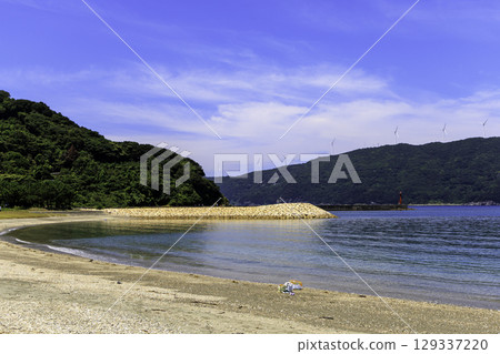 Summer scenery of Moon Beach Inoura and the breakwater from the sandy beach, with windmills visible in the distance 129337220