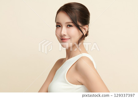 A beautiful young Asian woman with clean, fresh skin against a beige background. Skincare, facial treatment, cosmetology, beauty, and spa. An elegant portrait of an Asian woman. A beautiful young Asian woman with clean, fresh skin against a beige background. Skincare, facial treatment, cosmetology, beauty, and spa. An elegant portrait of an Asian woman. 129337397