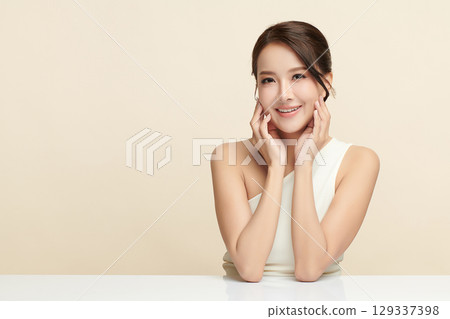 A beautiful young Asian woman with clean, fresh skin against a beige background. Skincare, facial treatment, cosmetology, beauty, and spa. An elegant portrait of an Asian woman. A beautiful young Asian woman with clean, fresh skin against a beige background. Skincare, facial treatment, cosmetology, beauty, and spa. An elegant portrait of an Asian woman. 129337398