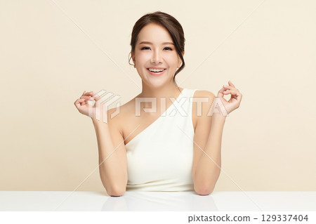 A beautiful young Asian woman with clean, fresh skin against a beige background. Skincare, facial treatment, cosmetology, beauty, and spa. An elegant portrait of an Asian woman. A beautiful young Asian woman with clean, fresh skin against a beige background. Skincare, facial treatment, cosmetology, beauty, and spa. An elegant portrait of an Asian woman. 129337404