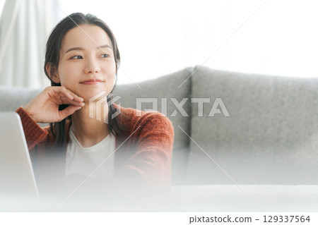 在客廳裡操作個人電腦的女人 在客廳裡操作個人電腦的女人 129337564