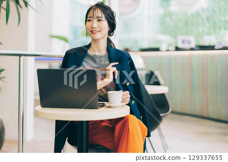 A stylish middle-aged woman using a computer in a cafe 129337655