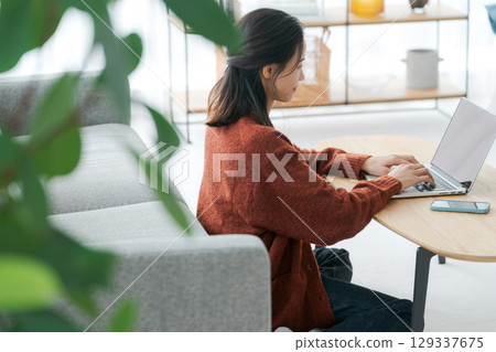 A woman who operates a personal computer in the living room A woman who operates a personal computer in the living room 129337675