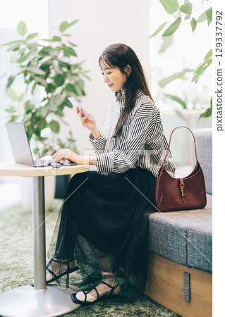 A woman using a computer in a cafe 129337792