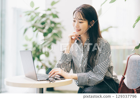 A woman using a computer in a cafe 129337796