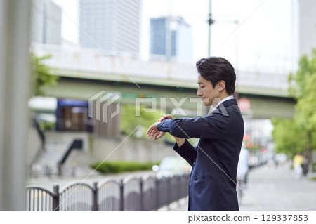 A business person in a suit waiting for a bus at a bus stop 129337853