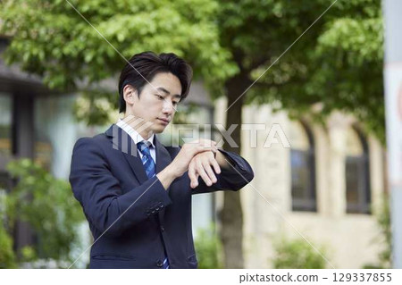 一位西裝革履的商人在公車站等車 129337855