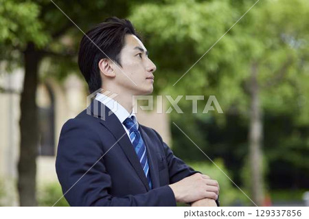 一位西裝革履的商人在公車站等車 129337856
