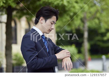 一位西裝革履的商人在公車站等車 129337857