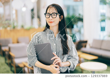 辦公室裡拿著筆記型電腦的女商人 129337869