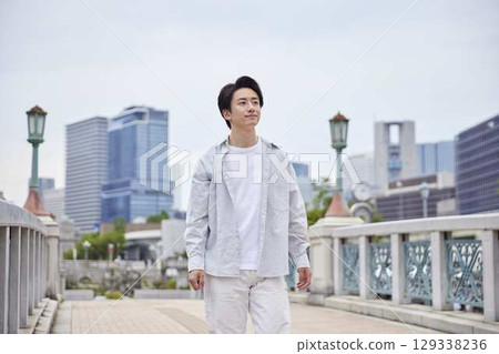 一位身著休閒服的日本年輕男子在假期期間在公園散步 一位身著休閒服的日本年輕男子在假期期間在公園散步 129338236