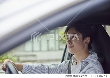 一位年輕的日本男子開車時,從駕駛座上向前看,這是他的側臉照出的畫面。 一位年輕的日本男子開車時,從駕駛座上向前看,這是他的側臉照出的畫面。 129338241