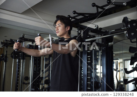 Young Japanese man in sportswear doing strength training at a fitness gym 129338248