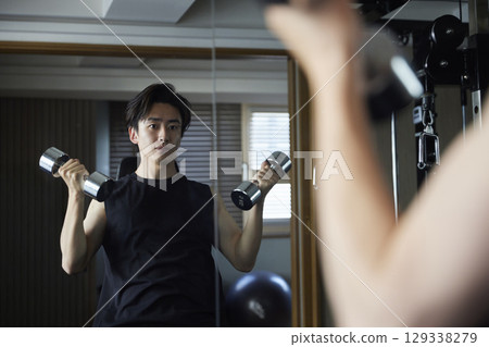 Young Japanese man in sportswear doing strength training at a fitness gym Young Japanese man in sportswear doing strength training at a fitness gym 129338279