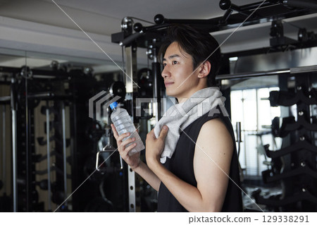 A young man with a towel and a drink at a fitness gym A young man with a towel and a drink at a fitness gym 129338291
