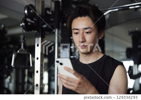 A young man looks at his smartphone during a break from training. A young man looks at his smartphone during a break from training. 129338293