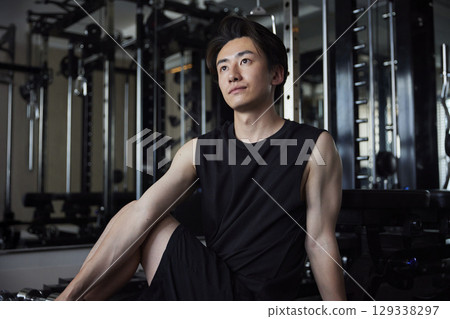 一位年輕男子在健身房做放鬆伸展運動。 一位年輕男子在健身房做放鬆伸展運動。 129338297