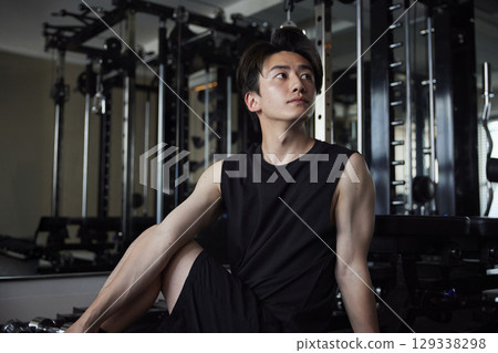 一位年輕男子在健身房做伸展運動,以提高身體柔軟度。 一位年輕男子在健身房做伸展運動,以提高身體柔軟度。 129338298