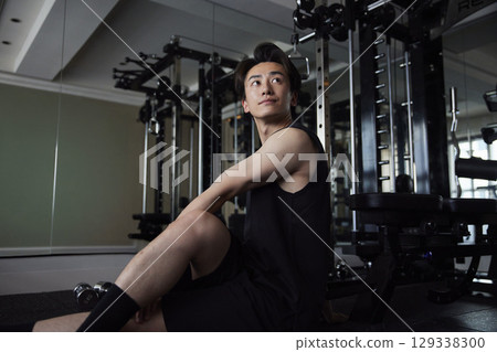 一位年輕男子在健身房做熱身伸展運動。 129338300