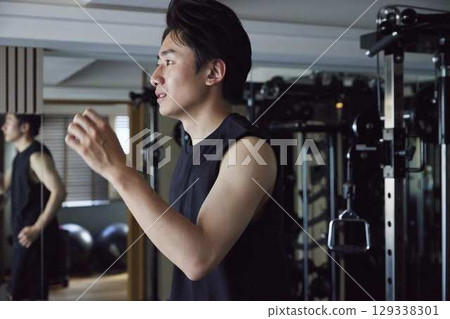 一位年輕男子在健身房的跑步機上鍛鍊耐力。 一位年輕男子在健身房的跑步機上鍛鍊耐力。 129338301