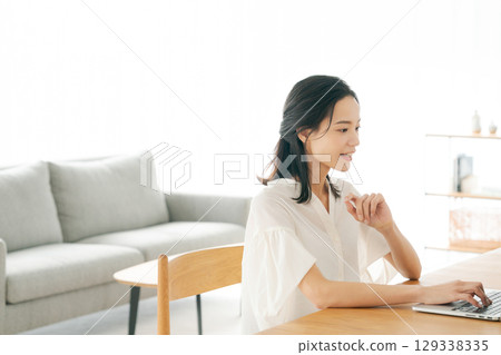 A woman using a personal computer at home A woman using a personal computer at home 129338335
