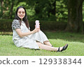 A young woman sitting on the grass and taking a break drinking water from a water bottle 129338344