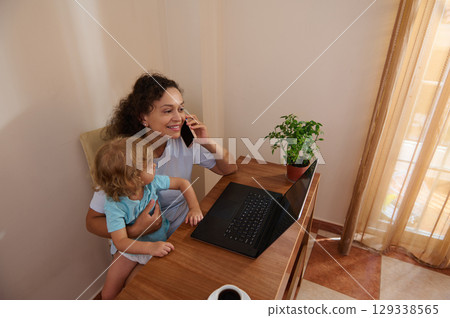 Mother Balancing Work and Family in Cozy Home Office Environment 129338565
