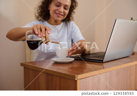 Relaxed Freelancer Enjoying Coffee While Working Remotely from a Cozy Home Office Setting Relaxed Freelancer Enjoying Coffee While Working Remotely from a Cozy Home Office Setting 129338593