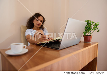 Woman Working Remotely in a Cozy Home Office Setting with Laptop 129338594
