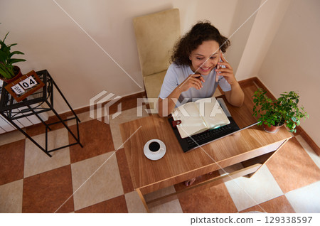 Remote Work from Home Featuring a Woman Speaking on the Phone at a Desk Remote Work from Home Featuring a Woman Speaking on the Phone at a Desk 129338597