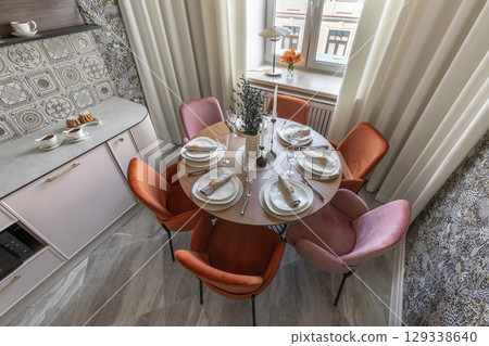 Top View of Stylish Kitchen Table Setting with Velvet Chairs 129338640