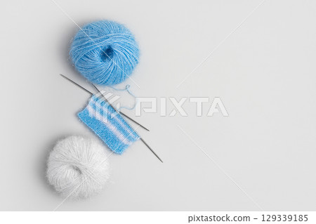 Blue and white knitted wool on gray background with knitting needles for knitting warm clothes and hobbies needlework 129339185