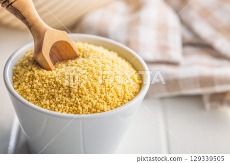 Raw couscous in bowl on white table. Raw couscous in bowl on white table. 129339505