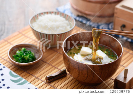 熱氣騰騰的味噌湯，配上碎海帶、豆腐和白米飯。日式早餐，家常菜，健康餐飲的形象。 129339776