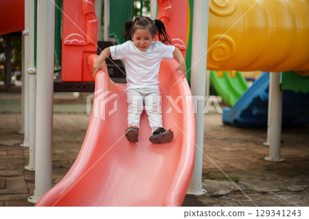 happy toddler baby girl sliding and playing at playground happy toddler baby girl sliding and playing at playground 129341243