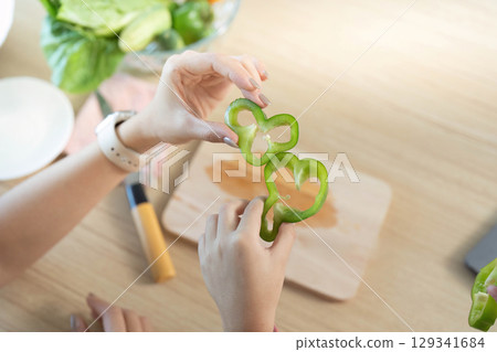 Healthy Cooking. Woman preparing fresh green bell pepper in kitchen for nutritious meal. Healthy Cooking. Woman preparing fresh green bell pepper in kitchen for nutritious meal. 129341684