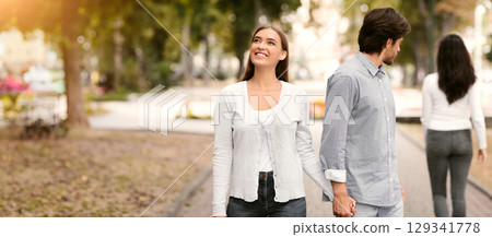 Lustful Cheating Boyfriend Looking At Other Woman Walking With Girlfriend In Park Outdoors. Selective Focus 129341778