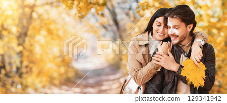 Loving woman with yellow leaves hugging her handsome husband from behind, time together at autumn forest, copy space Loving woman with yellow leaves hugging her handsome husband from behind, time together at autumn forest, copy space 129341942