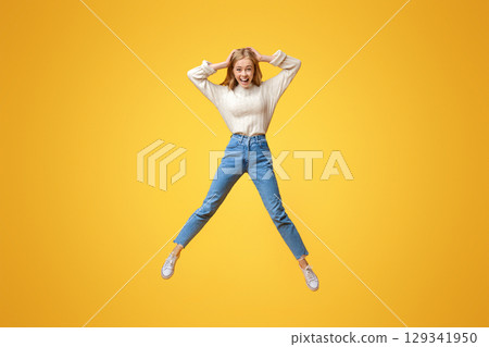 Unbelievable sales. Excited girl jumping in air with hands on head 129341950