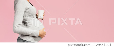Healthy diet during pregnancy. Lady holding glass of milk, pink background with copy space, side view Healthy diet during pregnancy. Lady holding glass of milk, pink background with copy space, side view 129341991