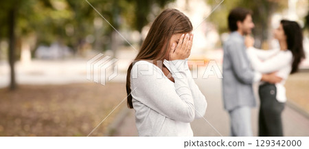 Upset woman crying, seeing her boyfriend with other girl in park 129342000