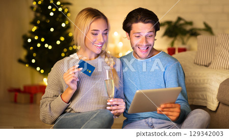 Preparing for Christmas. Happy couple buying gifts online, using tablet and credit card Preparing for Christmas. Happy couple buying gifts online, using tablet and credit card 129342003
