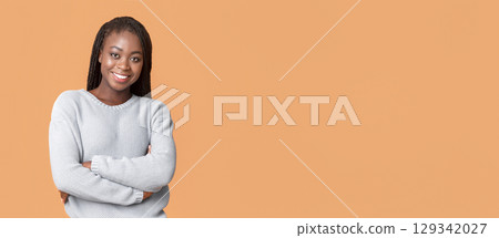 Confident young black woman posing in blue winter sweater over beige studio background, panorama with copy space Confident young black woman posing in blue winter sweater over beige studio background, panorama with copy space 129342027