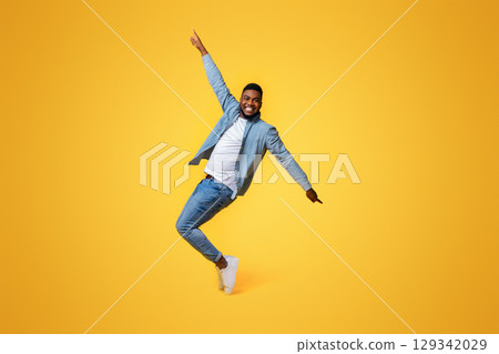 Cheerful Black Standing On Tiptoes, Fooling Over Yellow Background In Studio 129342029