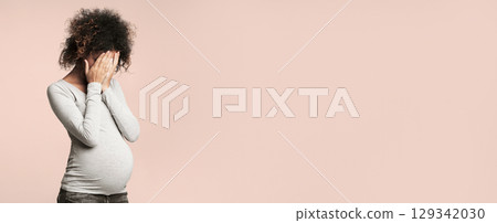 Depression during pregnancy. Afro woman covering face with hands and crying, grey background Depression during pregnancy. Afro woman covering face with hands and crying, grey background 129342030